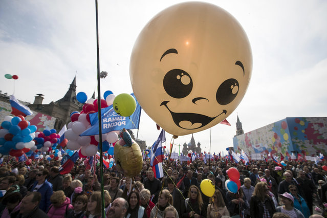 Balloons and flags fly over the crowd as people walk on Red Square to mark May Day in Moscow, with St. Basil's Cathedral center in the background, Russia, Tuesday, May 1, 2018.  As in Soviet times, people paraded across Red Square, but instead of red flags with the Communist hammer and sickle, they waved the Russian tricolor. (Photo by Pavel Golovkin/AP Photo)