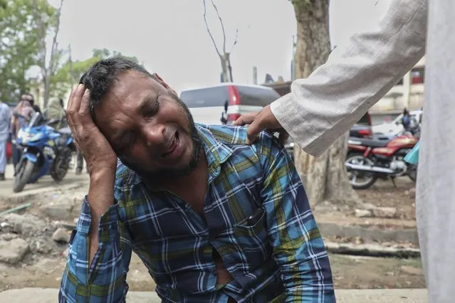 An unidentified man grieves as relatives receive bodies of victims of a road accident after a bus fell into a roadside ditch in Shibchar area in Madaripur district, Bangladesh, Sunday, March 19, 2023. (Photo by Jibon Ahmed/AP Photo)