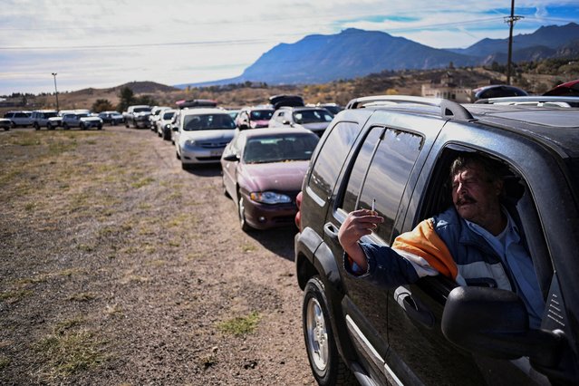 Randy Binder smokes a cigarette while waiting for hours in a queue of more than 100 cars at the Mt. Carmel Veterans Service Center food distribution site in Colorado Springs, Colorado, on November 7, 2025. (Photo by Mark Makela/Reuters)