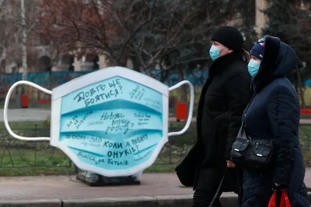 Women walk past an installation showing a protective face mask amid the coronavirus disease (COVID-19) outbreak in Kyiv, Ukraine on December 28, 2020. (Photo by Valentyn Ogirenko/Reuters)