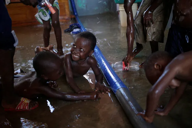 Children play with the water coming out of a hose at a temporary shelter after Hurricane Matthew hit Jeremie, Haiti, October 31, 2016. (Photo by Andres Martinez Casares/Reuters)