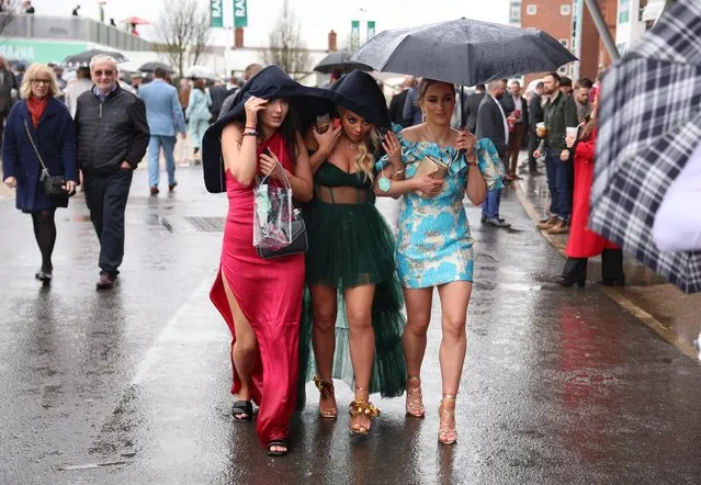 General view as racegoers shield themselves from the rain on Ladies Day at Aintree Racecourse in Liverpool, Britain on April 14, 2023. (Photo by Phil Noble/Reuters)