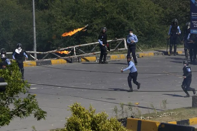 A supporter of Pakistan's former Prime Minister Imran Khan throws a petrol bomb toward police officers during clashes, in Islamabad, Pakistan, Wednesday, May 10, 2023. A court has ruled that former Pakistani Prime Minister Imran Khan can be held for questioning for eight days. The decision Wednesday comes a day after the country’s popular opposition leader was dragged from a courtroom and arrested. His detention set off clashes between his supporters and police Tuesday. (Photo by Anjum Naveed/AP Photo)