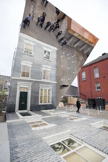 A large-scale installation art piece by Leandro Erlich, named “Dalston House”, is displayed on June 24, 2013 in London, England. Part of the “Beyond Barbican” summer series of events, the interactive installation is a full facade of a late nineteenth-century Victorian terraced house built on the ground with a large mirror above it to reflect people as to appear dangling from the structure.  (Photo by Dan Dennison/Getty Images)