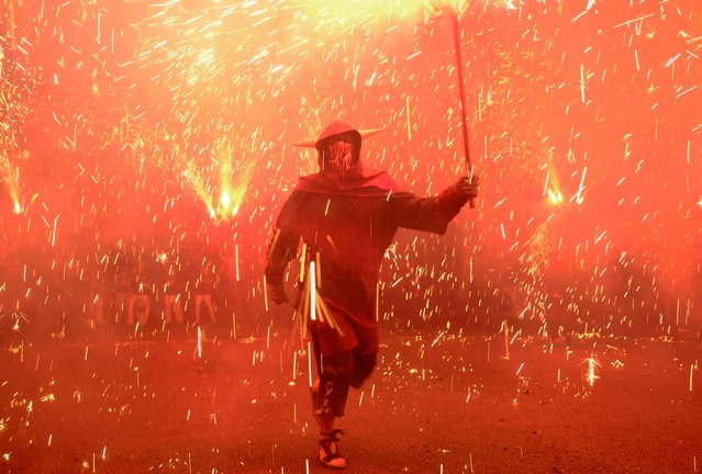 A performer dressed as a devil holds a stick spewing fire sparks during the traditional “Correfoc” (fire run) to mark Barcelona's patroness, La Merce, in Barcelona, Spain on September 21, 2024. (Photo by Nacho Doce/Reuters)
