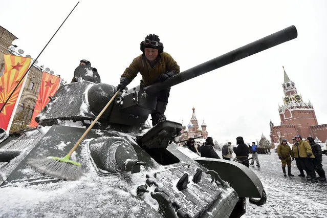 A participant dressed in a historical uniform sweeps snow off a WWII-era Red Army tank before taking part in the parade at Red Square in Moscow on November 7, 2016. Russia marks the 75th anniversary of the 1941 historical parade, when Red Army soldiers marched past the Kremlin walls towards the front line to fight the Nazi Germany troops during World War Two. (Photo by Natalia Kolesnikova/AFP Photo)