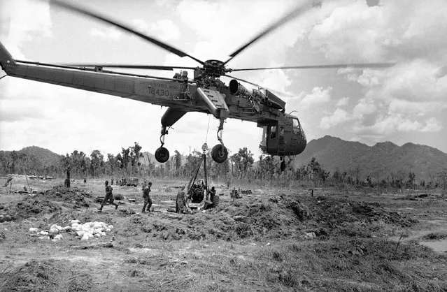 An artilleryman of the U.S. 1st Air Cavalry division stands atop a 105mm Howitzer, signaling a helicopter which later picked it up and flew it out of the a Shau Valley on May 16, 1968. The U.S. command in South Vietnam closed out month-long operation Delaware on May 17, leaving the valley to the North Vietnamese. (Photo by Dana Stone/AP Photo)
