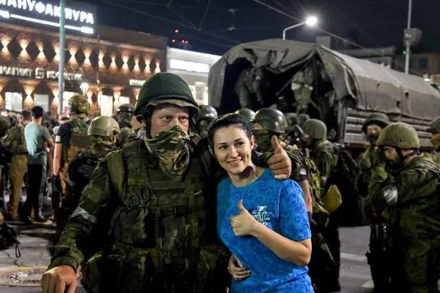 A local woman poses with private military company (PMC) Wagner Group serviceman as he prepares to leave downtown Rostov-on-Don, southern Russia, 24 June 2023. Security and armoured vehicles were deployed after the Chief of the private military company (PMC) Wagner Group said in a video that his troops had occupied the building of the headquarters of the Southern Military District, demanding a meeting with Russia's defense chiefs. The President of Belarus held talks with the head of the Wagner group, as a result of which he accepted a proposal to stop the movement of the group's fighters across Russia, the press service of the President of Belarus reported. The Chief of Wagner Group has said that columns of his group will return to field camps. (Photo by Arkady Budnitsky/EPA)
