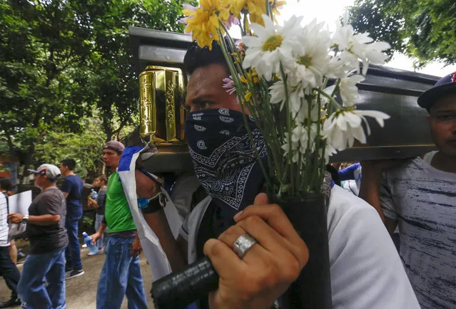 Friends and family carry the coffin with the body of Gerald Vasquez, an engineering student that was killed during the July 14 attack by police and paramilitary forces to the National University of Managua, to be buried in Managua, Nicaragua, Monday, July 16, 2018. The onslaught was televised by local media outlets and covered by three local journalists who reported via Facebook Live. Students fearing for their lives sent farewell messages to friends and family. “I did it for the country and I don't regret it”, a crying girl said in a video that went viral. “Forgive me mama, I love you”. (Photo by Alfredo Zuniga/AP Photo)