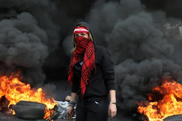 A demonstrator stands near a burning fire blocking a road, during a protest against the fall in Lebanese pound currency and mounting economic hardships, in Zouk, Lebanon on March 8, 2021. (Photo by Mohamed Azakir/Reuters)