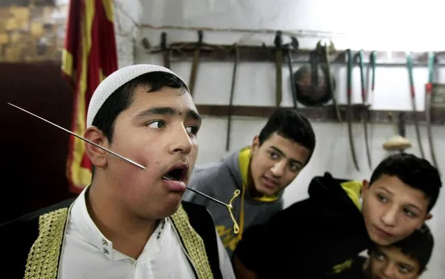 Lebanese boys look at a Muslim Sufi who pierced his cheek with metal during a religious ritual to mark Prophet Muhammad's birthday, in the southern port city of Sidon, Lebanon, Wednesday, December 23, 2015. (Photo by Mohammed Zaatari/AP Photo)