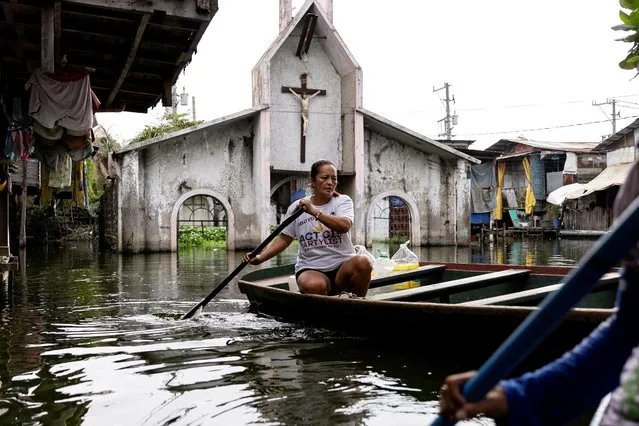 A woman paddles through the flooded Artex Compound in Malabon, Metro Manila, Philippines on July 4, 2023. (Photo by Eloisa Lopez/Reuters)