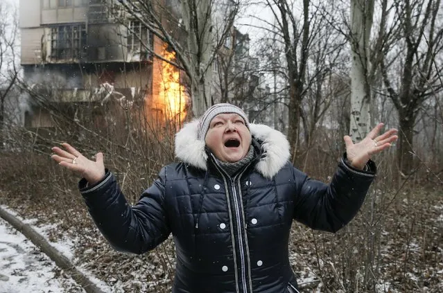 A woman reacts as the residential block (back) in which she lives in burns, a result of recent shelling according to locals, on the outskirts of Donetsk, eastern Ukraine February 9, 2015. (Photo by Maxim Shemetov/Reuters)