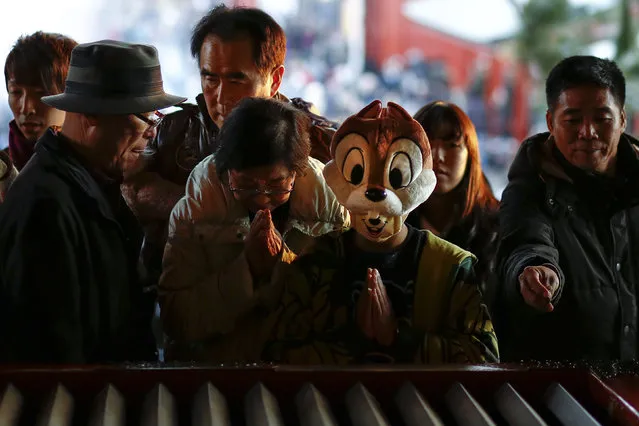 A boy wears a comic character hat as he prays at the Sensoji temple ahead of the New Year holidays in Tokyo, Japan December 30, 2015. (Photo by Thomas Peter/Reuters)