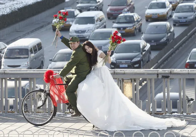 An engaged couple sits on a bicycle as they pose for wedding photographs to the theme of “naked wedding”, on a pedestrian bridge on Valentine's Day in central Beijing February 14, 2011. “Naked wedding” is a popular new expression in China which means young couples get married with no houses, cars or little bank savings. (Photo by Reuters/China Daily)