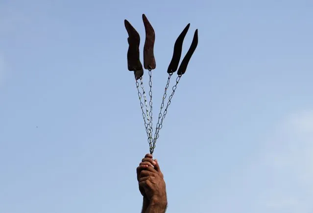 A Shiite Muslim flagellates himself with knifes on chains during a procession to mark Ashoura, in Islamabad, Pakistan, Friday, July 28, 2023. Ashoura is the Shiite Muslim commemoration marking the death of Hussein, the grandson of the Prophet Muhammad, at the Battle of Karbala in present-day Iraq in the 7th century. (Photo by Rahmat Gul/AP Photo)