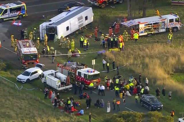 In this image made from video, rescue workers help children from a school bus that rolled onto its side on the outskirts of Melbourne, Australia, Tuesday, May 16, 2023. Seven children remain hospitalized Wednesday, May 17, with serious injuries after a truck struck a school bus Tuesday carrying as many as 45 students in southeastern Australia. (Photo by AuBC/CHANNEL 7/CHANNEL 9 via AP Photo)
