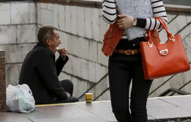 A man eats his sandwich as he begs money near an underground passage in central Kiev, Ukraine, September 9, 2015. (Photo by Gleb Garanich/Reuters)