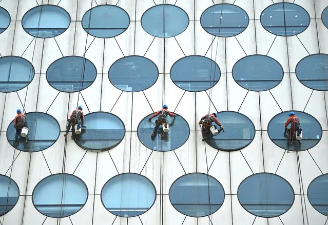 Workers clean the windows of a building in Beijing on May 12, 2021. (Photo by Noel Celis/AFP Photo)