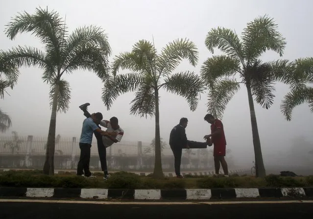 Men stretch during their routine exercises on a road divider during a foggy morning in Agartala, India, January 11, 2016. (Photo by Jayanta Dey/Reuters)