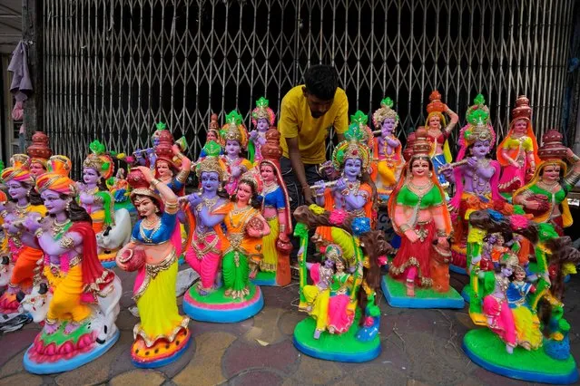 A man arranges Idols of Hindu god Krishna and his consort Radha for sale ahead of the Hindu Festival Janmashtami in Ahmedabad, India, Wednesday, September 6, 2023. Janmashtami celebrates  the birth of Krishna. (Photo by Ajit Solanki/AP Photo)