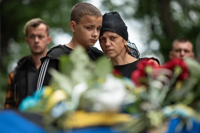 Svitlana Nazarenko, sister of Mykhailo Tereshchenko, is being comforted by her son during her brother's funeral on June 14, 2022 in Kyiv, Ukraine. Mykhailo Tereschchenko, 50, was a Ukrainian soldier who was killed in the Ukrainian region of Donbas. (Photo by Alexey Furman/Getty Images)