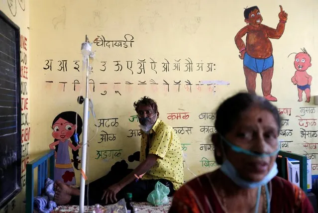 Patients suffering from coronavirus disease (COVID-19) receive oxygen support as they sit inside a classroom turned COVID-19 care facility on the outskirts of Mumbai, India, May 24, 2021. (Photo by Francis Mascarenhas/Reuters)