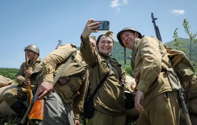 Members of historical military clubs, dressed in World War Two uniforms, pose for a selfie before the historical re-enactment of the Battle of the Caucasus, in the town of Lermontov, in Stavropol region, Russia on May 29, 2021. (Photo by Eduard Korniyenko/Reuters)