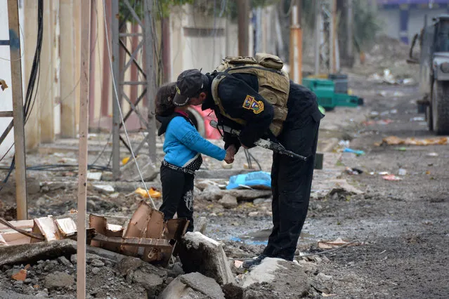 A member of Iraqi special forces kisses a child in the neighbourhood of al-Barid east of Mosul on December 18, 2016 during their ongoing operation against Islamic State (IS) group jihadists to wrest back the city. (Photo by Mahmoud Al-Samarrai/AFP Photo)