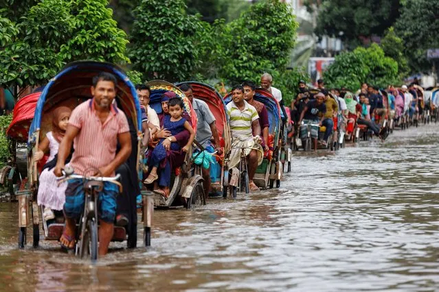 Commuters ride on rickshaws on a flooded road after heavy rains in Dhaka, Bangladesh on September 22, 2023. (Photo by Mohammad Ponir Hossain/Reuters)