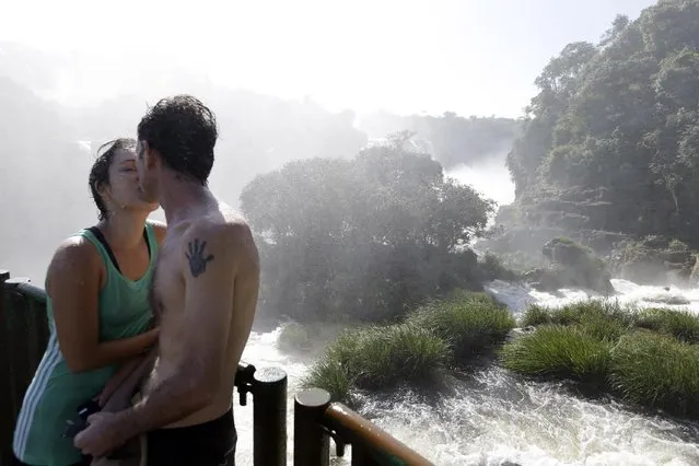 In this March 14, 2015 photo, Brazilians Lilian and Edgardo kiss in the spray of Iguazu Falls in Brazil. Local indigenous legend has it that serpent god Boi, furious over a broken heart, created the falls by shattering the Iguazu river’s flow to prevent the maiden Naipu from escaping in a canoe with her lover Taroba. The legend says the rainbows that grace the waters are the souls of Naipu and Taroba reuniting. (Photo by Jorge Saenz/AP Photo)