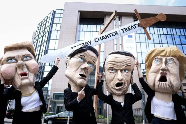Environmental activists, wearing masks mimicking EU leaders (L/R): EU Commission President Ursula von der Leyen, Netherlands' Prime Minister Mark Rutte, France's President Emmanuel Macron and Germany's Chancellor Angela Merkel, pose outside the European Council building in Brussels on July 6, 2021. Four hundred worldwide civil society organisations have sent an open letter to EU leaders to call on the EU and its member states to exit the threat of the Energy Charter Treaty (ECT) by the UN Climate Summit in November 2021 in Glasgow. (Photo by Kenzo Tribouillard/AFP Photo)