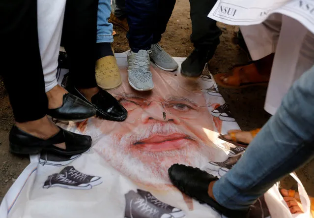 Members of National Students' Union of India (NSUI), the student wing of India's main opposition Congress party, step on a banner with a portrait of India's Prime Minister Narendra Modi during a protest against what they say is cash shortages weeks after Modi's decision to scrap high-value bank notes, in Ahmedabad, India, December 30, 2016. (Photo by Amit Dave/Reuters)