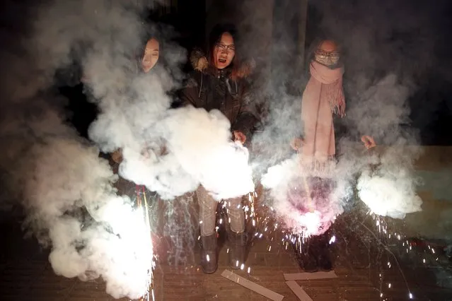 Women celebrate the start of the Chinese Lunar New Year of Monkey with firecrackers in Beijing early February 8, 2016. (Photo by Damir Sagolj/Reuters)