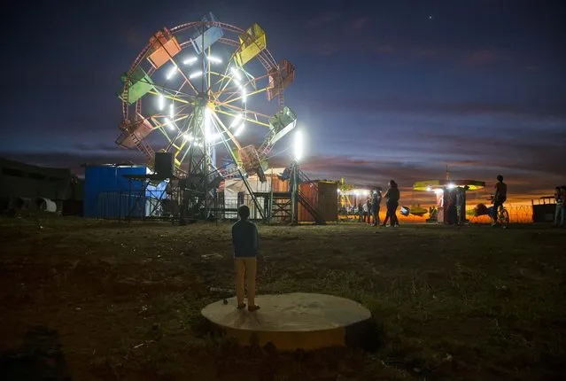 A girl who didn't enter the fair stands outside the entrance for few minutes before leaving, in El Crucero, Nicaragua, Sunday, March 30, 2015. The town holds a fair once a year to celebrate its founding. (Photo by Esteban Felix/AP Photo)