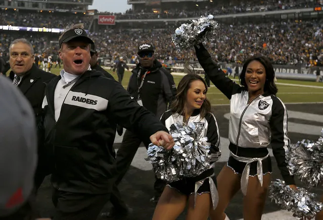 Oakland Raiders head coach Jon Gruden gestures toward fans as he walks with cheerleaders after the Raiders beat the Pittsburgh Steelers in an NFL football game in Oakland, Calif., Sunday, December 9, 2018. (Photo by D. Ross Cameron/AP Photo)