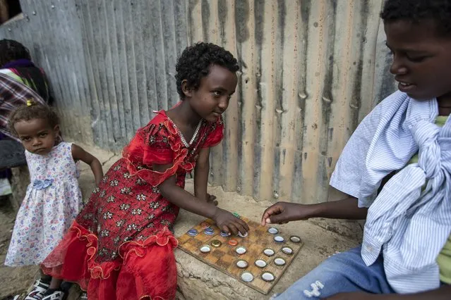 Elena, 7, left, plays a game of checkers using soda bottle tops with friend Hailemariam, 12, at a reception and day center for displaced Tigrayans in Mekele, in the Tigray region of northern Ethiopia, Sunday, May 9, 2021. The Tigray conflict has displaced more than 1 million people, the International Organization for Migration reported in April, and the numbers continue to rise. Some thousands of Eritrean refugees are among the most vulnerable groups in the Tigray conflict and are increasingly caught in the middle of the conflict in Ethiopia’s Tigray region. (Photo by Ben Curtis/AP Photo)