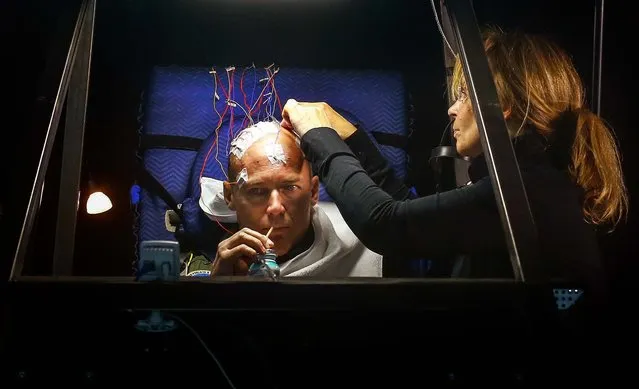 A medic connects electrodes to the head of Bertrand Piccard, pilot and co-founder of Solar Impulse, before the start of a 72-hour transatlantic flight simulation at the airport in Duebendorf, on December 17, 2013. Swiss long-range solar-powered aircraft project Solar Impulse HB-SIB airplane is expected to be completed by the end of 2013. Flight testing is planned for spring 2014, and the first solar-powered round-the-world flight for sometime between April and July 2015. (Photo by Arnd Wiegmann/Reuters)