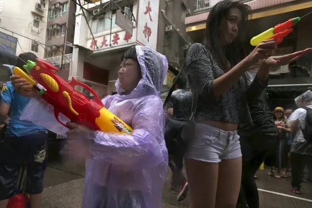 Revellers use water guns as they participate in a water fight during Songkran Festival celebrations at Kowloon City district, known as Little Thailand as there is large number of restaurants and shops run by Thais, in Hong Kong April 12, 2015. (Photo by Tyrone Siu/Reuters)