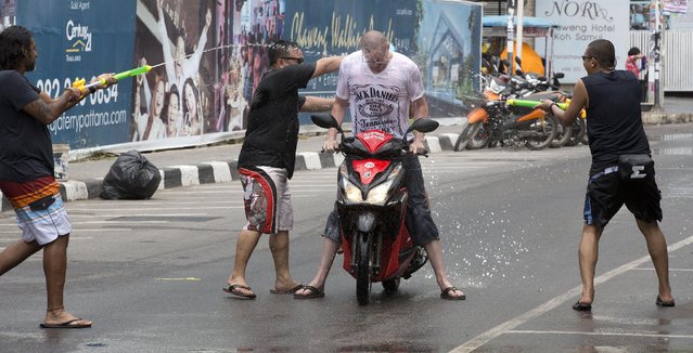A tourist is showered in water by locals during the Songkran festival to celebrate the Thai New Year on Samui Island in Surat Thani province, Thailand, Monday, April 13, 2015. (Photo by Mark Baker/AP Photo)