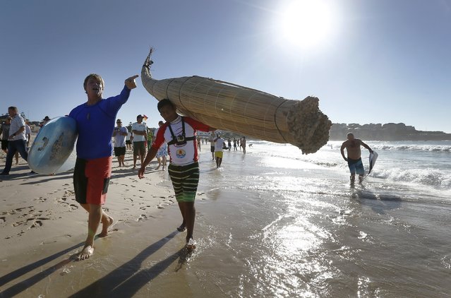 Australian champion surfer Cheyne Horan guides Peruvian surfer Carlos “Huevito” Areola, carrying his reed board, or “caballito” (little horse), into the ocean at Sydney's Bondi Beach, February 24, 2016. (Photo by Jason Reed/Reuters)