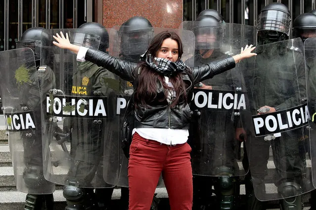 A woman stands in front of anti-riot police during a demonstration by students, union members and activists against local Government decisions, in Bogota, Colombia, 25 February 2016. Protesters gathered in the downtown square Plaza Bolivar, in Bogota, to protest against the increase of the public transport fees, to claim for salaries increasing and other problems, according to press reports. (Photo by Leonardo Muñoz/EPA)