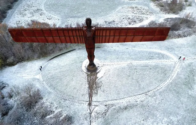 People walk next to Antony Gormley's Angel of the North as snow continues to fall in Gateshead, Britain on November 30, 2023. (Photo by Lee Smith/Reuters)