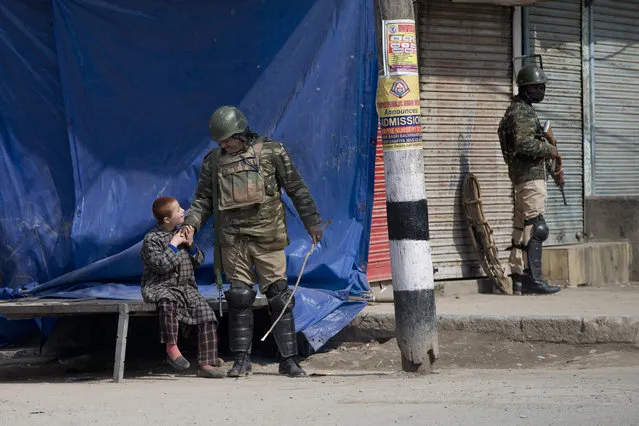 An Indian paramilitary soldier plays with a Kashmiri child as he stands guard during security lockdown in Srinagar, Indian controlled Kashmir, Sunday, Februaary 24, 2019. Shops and businesses have closed in Kashmir to protest a sweeping crackdown against activists seeking the end of Indian rule in the disputed region. (Photo by Dar Yasin/AP Photo)