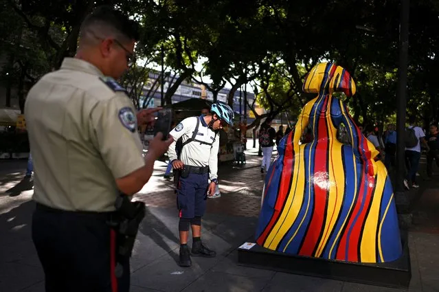 Law enforcement officers take pictures of a sculpture by Venezuelan artist Antonio Azzato as part of the “Meninas Caracas Gallery” street exhibit which pays homage to Spanish artist Diego Velazquez’s “Las Meninas” in Caracas, Venezuela on January 10, 2024. (Photo by Gaby Oraa/Reuters)