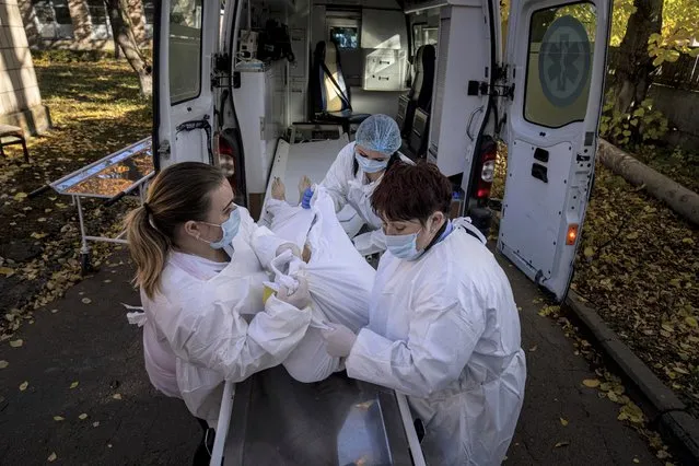 Medical staff members load a body of a patient who died of coronavirus at the morgue of the city hospital 1 in Rivne, Ukraine, Friday, October 22, 2021. In Rivne, 300 kilometers (190 miles) west of Kyiv, the city hospital is swamped with COVID-19 patients and doctors say the situation is worse than during the wave of infections early in the pandemic that severely strained the health system. Ukraine's coronavirus infections and deaths reached all-time highs for a second straight day Friday, in a growing challenge for the country with one of Europe's lowest shares of vaccinated people. (Photo by Evgeniy Maloletka/AP Photo)