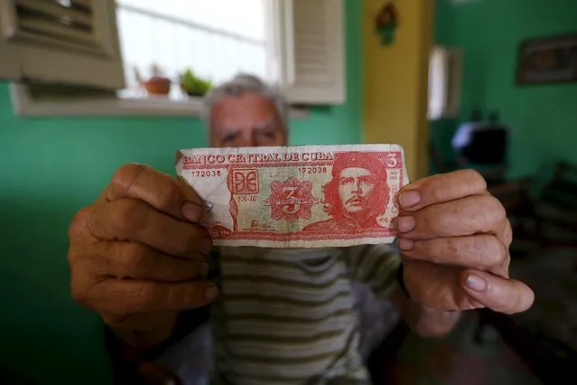 A man shows a bill printed with an image of late revolutionary hero Ernesto “Che” Guevara in Havana, March 18, 2016. (Photo by Ivan Alvarado/Reuters)