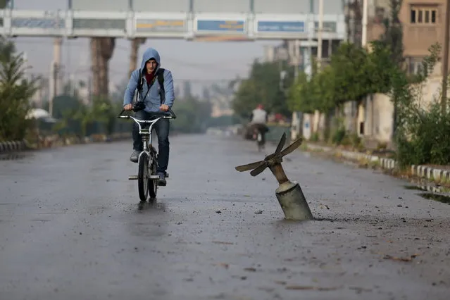 A resident rides his bicycle near what activists said was an exploded cluster bomb shell in the town of Douma, eastern Ghouta in Damascus November 5, 2015. (Photo by Bassam Khabieh/Reuters)