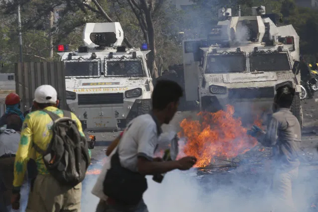 Opponents to Venezuela's President Nicolas Maduro face off with Bolivarian National Guards in armored vehicles who are loyal to the president, during an attempted military uprising in Caracas, Venezuela, Tuesday, April 30, 2019. (Photo by Ariana Cubillos/AP Photo)