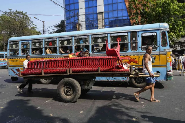 Two men carry plastic chairs on a handcart in Kolkata, India, Friday, March 8, 2024. (Photo by Bikas Das/AP Photo)